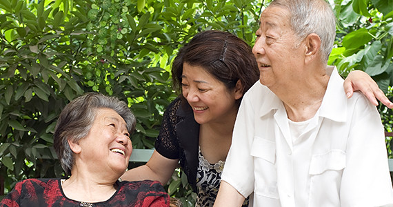 A happy older Asian couple and their daughter