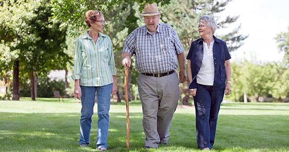 Three Latino seniors walking in park during the day