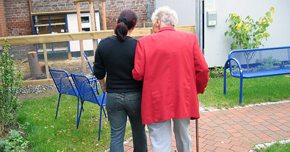 older person holding arm of caregiver while walking