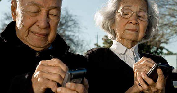 Older Asian couple using their mobile phones