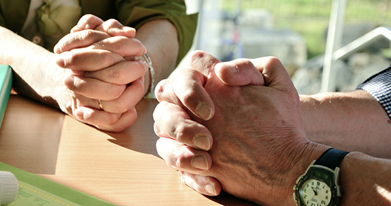 Hands of two people praying together