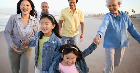 Asian multi-generational family walking and playing on the beach