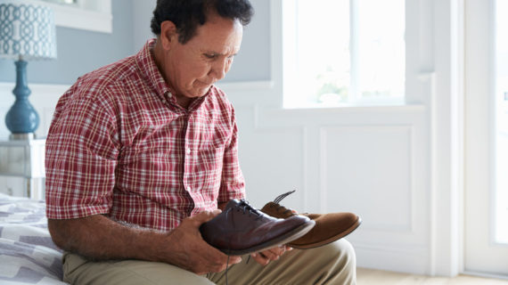 Senior Hispanic Man Suffering With Dementia Trying To Dress