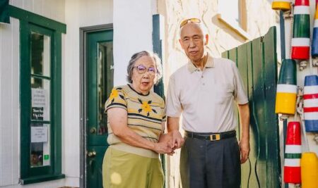 an elderly Pacific Islander man and woman standing on a colorful street corner