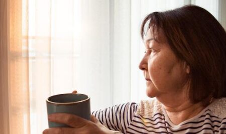 a women holding a cup of coffee while looking out a window
