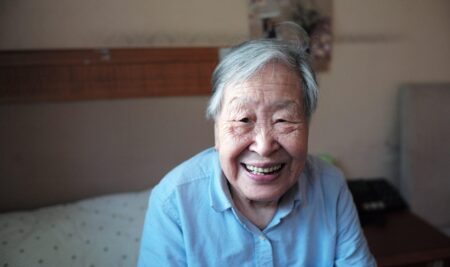 and elderly Asian woman sitting on a bed