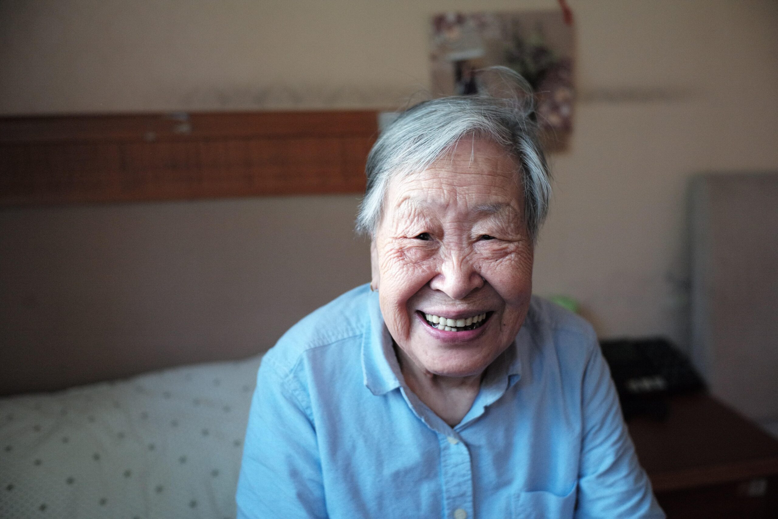 and elderly Asian woman sitting on a bed