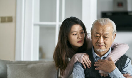 young asian adult daughter conforting senior father at home