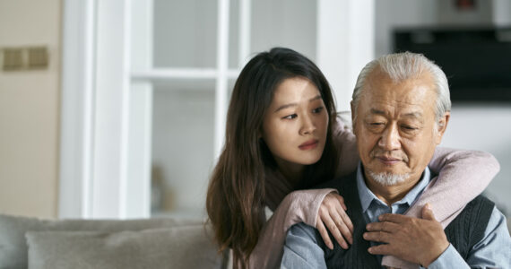 young asian adult daughter conforting senior father at home