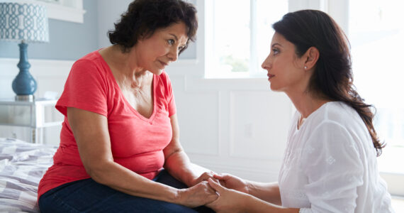 Adult Daughter Comforting Mother Suffering With Dementia